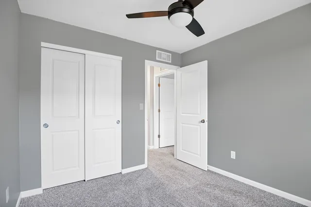a view of an empty room and chandelier fan