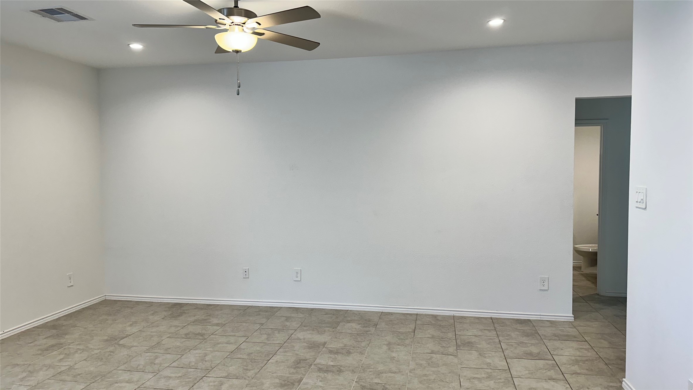 1103 Cattle Chute Court Rosharon, TX 77583 - Photo 7 of 26 This room features a spacious, open layout with neutral tile flooring and white walls, enhanced by recessed lighting and a ceiling fan. There's an adjacent doorway leading to another area, potentially a bathroom.