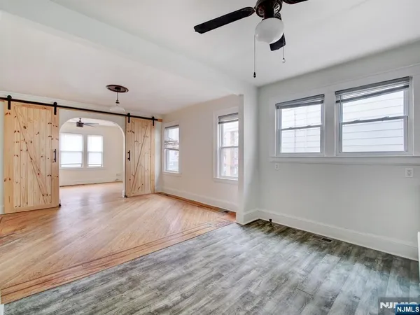 a view of an empty room with a window and wooden floor