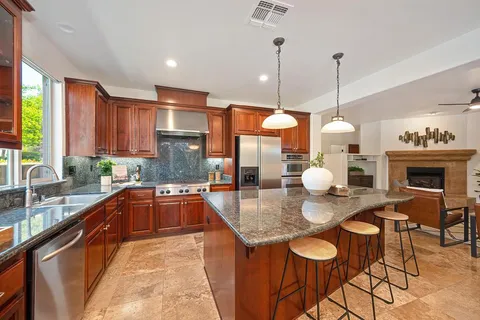 a kitchen with stainless steel appliances granite countertop a stove a sink a oven a dining table and chairs