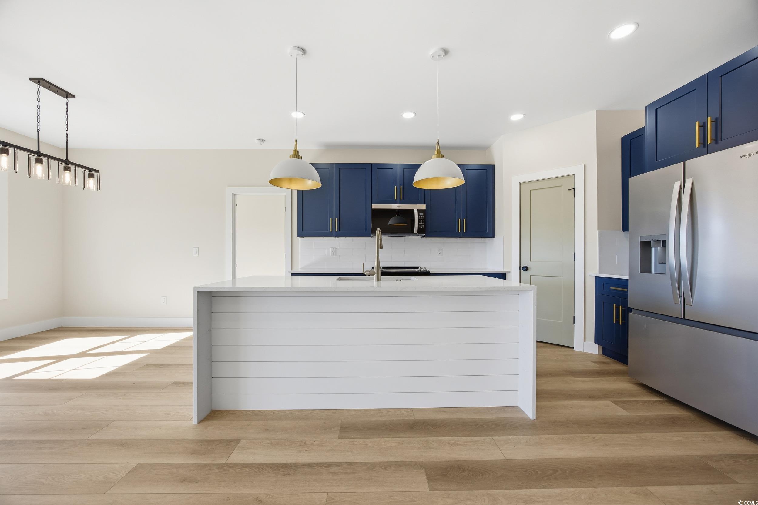 631 Highway 548 Conway Sc 29527 Conway, SC 29527 - Photo 10 of 40 Kitchen with blue cabinetry, stainless steel appliances, light stone counters, hanging light fixtures, and a kitchen island with sink