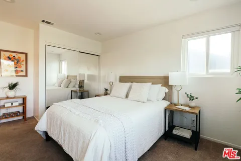 a bedroom with a bed and a lamp on dresser
