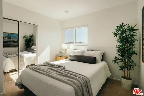 a bedroom with a large bed and a potted plant