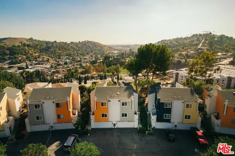 an aerial view of residential houses with outdoor space and trees