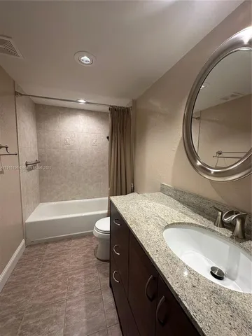 a bathroom with a granite countertop sink a toilet and bathtub
