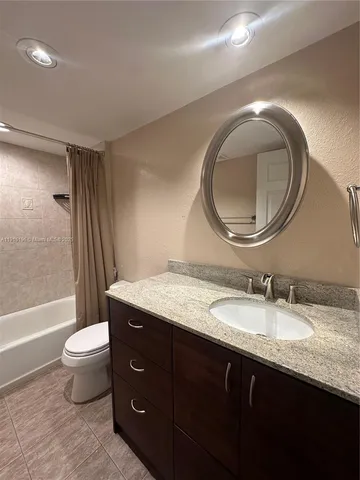 a bathroom with a granite countertop toilet a sink and a mirror