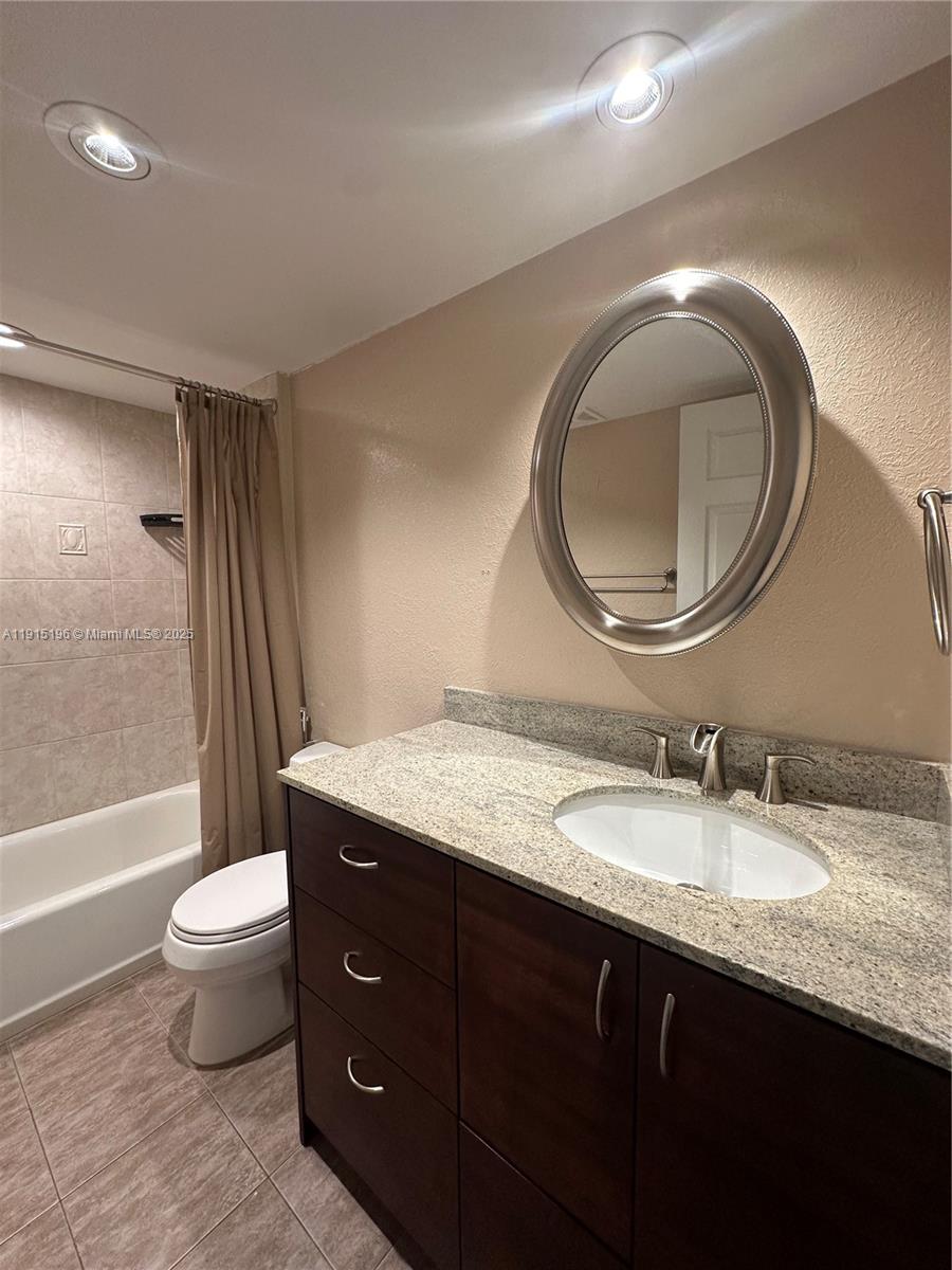 1526 Whitehall Drive, Unit 403 Davie, FL 33324 - Photo 15 of 16 a bathroom with a granite countertop toilet a sink and a mirror