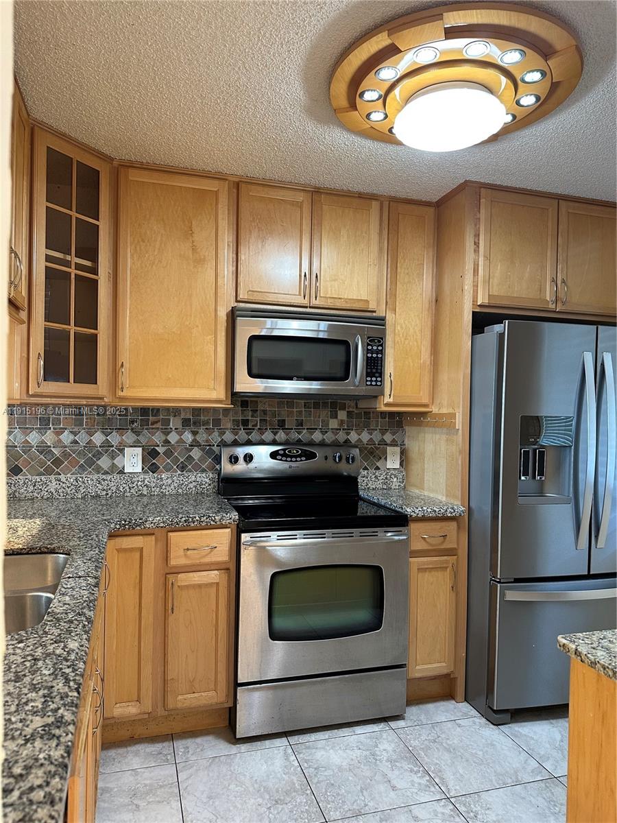 1526 Whitehall Drive, Unit 403 Davie, FL 33324 - Photo 2 of 16 a kitchen with granite countertop a stove and a microwave oven
