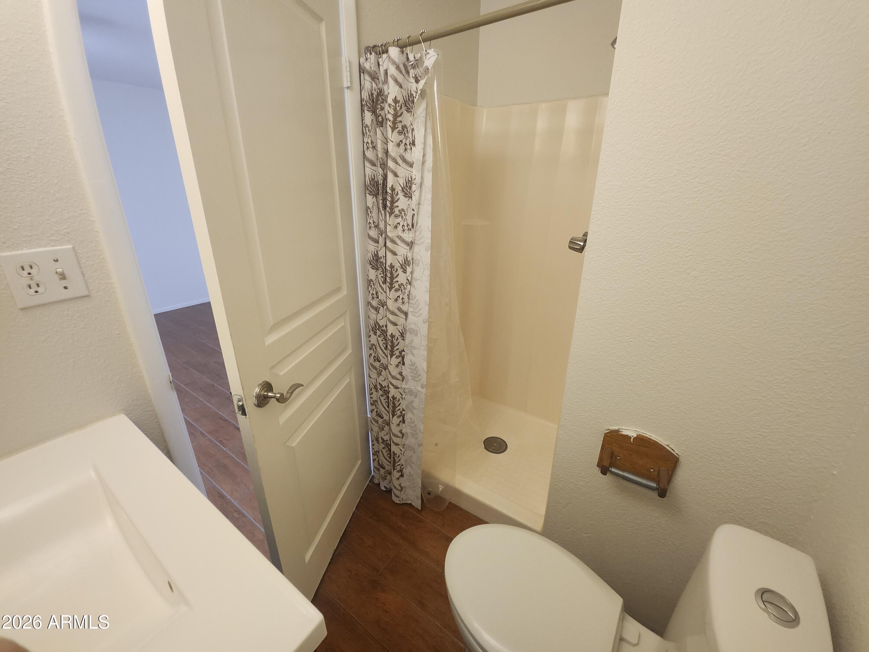 4325 East Vineyard Road Phoenix, AZ 85042 - Photo 3 of 8 a white toilet sitting next to a shower curtain