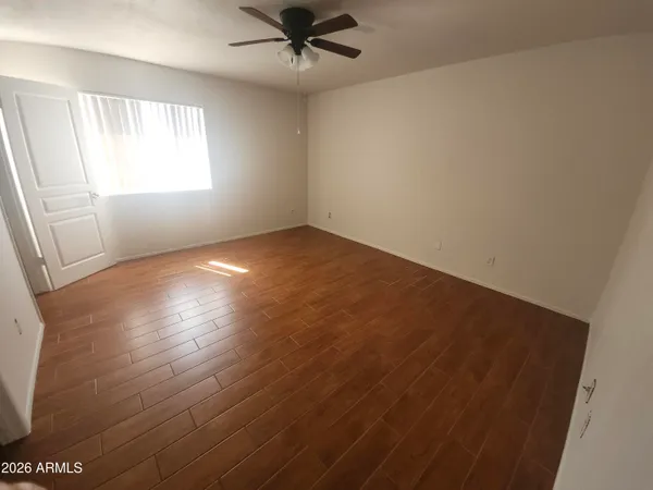 an empty room with wooden floor fan and windows
