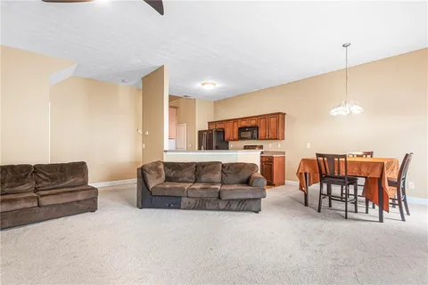 a living room with furniture kitchen view and a chandelier