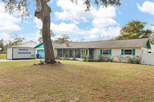 a front view of house with yard and trees in the background
