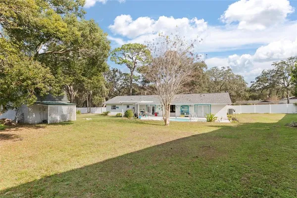 a view of a house with a big yard and large trees