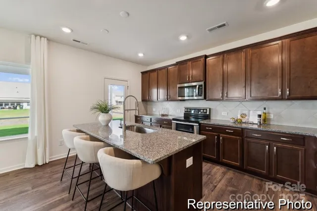 a kitchen with granite countertop a table chairs microwave and cabinets