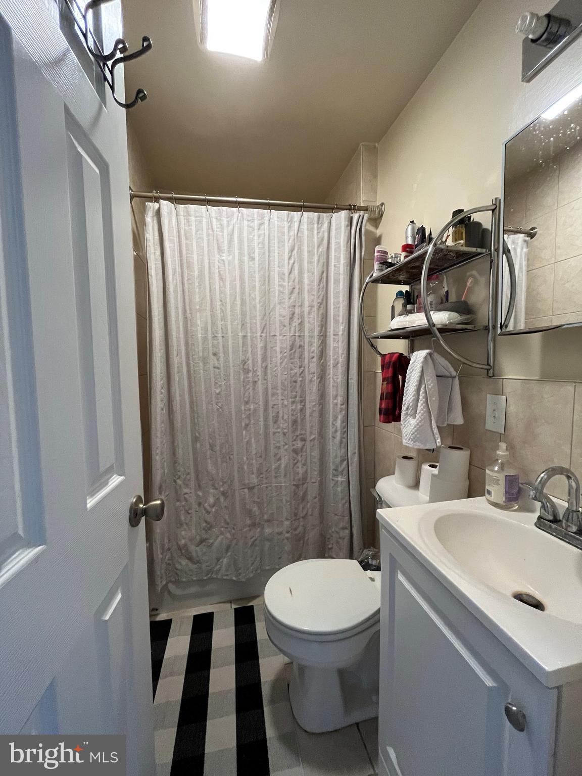 1429 West Norris Street, Unit 1 Philadelphia, PA 19121 - Photo 11 of 15 a bathroom with a sink a toilet a mirror and shower curtain