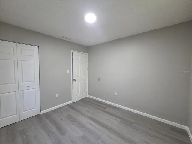 an empty room with wooden floor and entrance