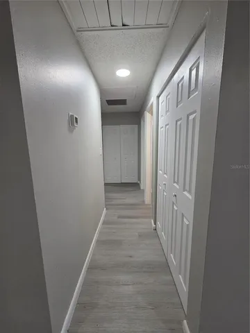 an empty room with wooden floor closet and windows
