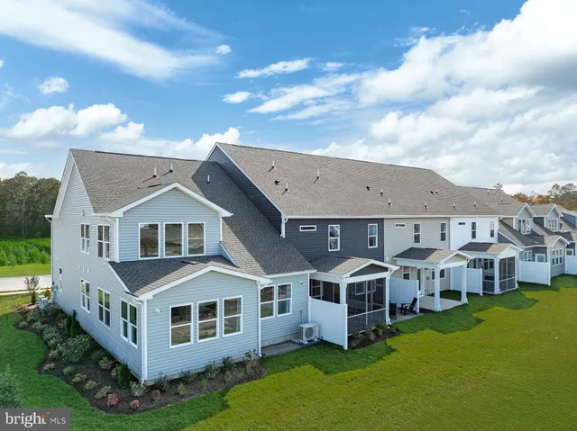 a aerial view of residential houses with yard and trees in the background