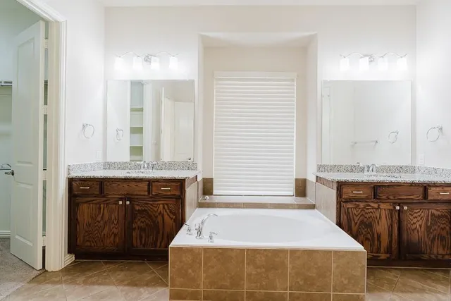 a spacious bathroom with a tub sink and mirror