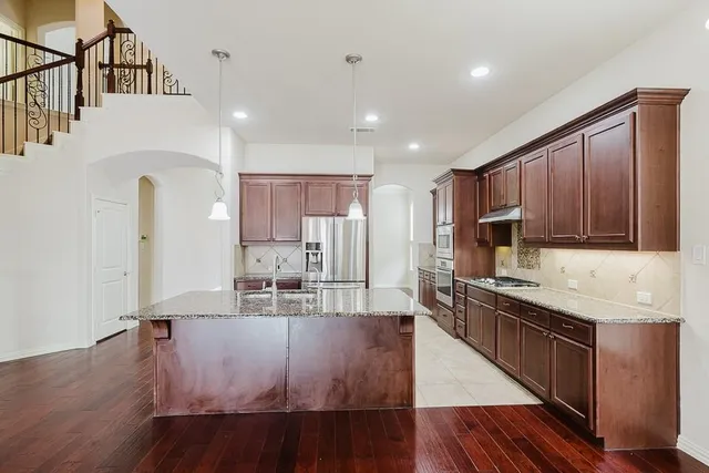 a kitchen with stainless steel appliances granite countertop a sink refrigerator and cabinets