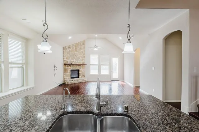 a view of a kitchen with granite countertop a sink stainless steel appliances and cabinets