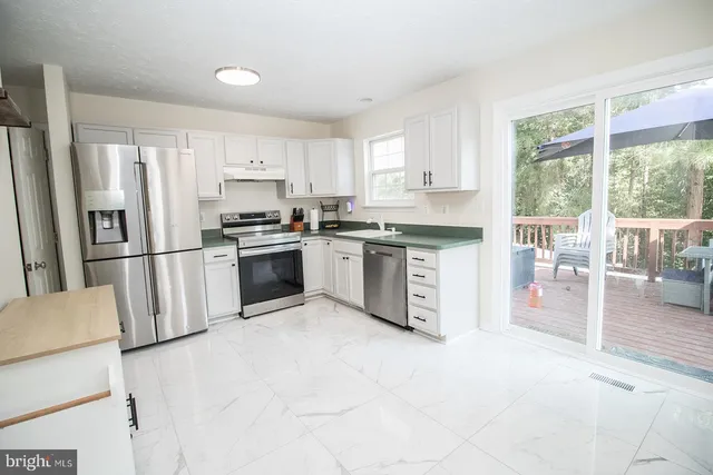 a kitchen with white cabinets stainless steel appliances and window