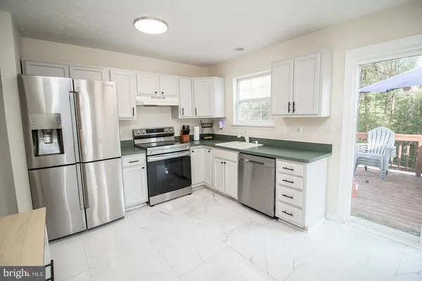a kitchen with granite countertop white cabinets and stainless steel appliances