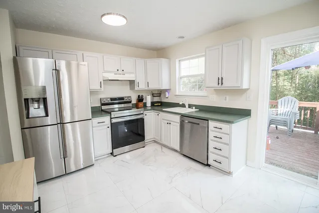 a kitchen with granite countertop white cabinets and stainless steel appliances