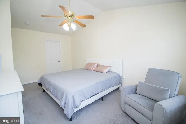 a bedroom with a bed couch and ceiling fan
