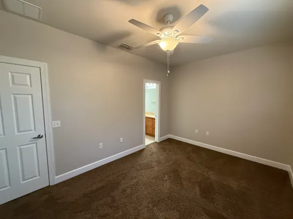 an empty room with a chandelier fan and windows