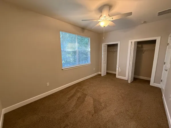 an empty room with windows and fan