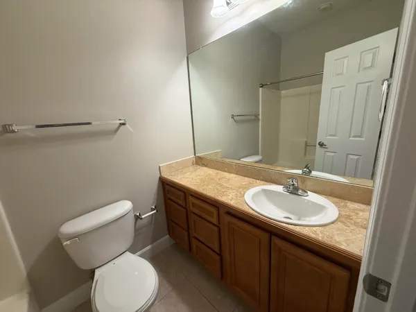 a bathroom with a granite countertop toilet sink and mirror