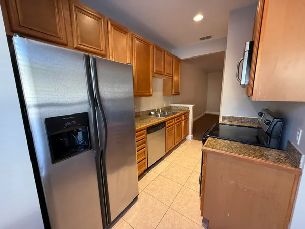 a kitchen with stainless steel appliances granite countertop a refrigerator a stove and a sink