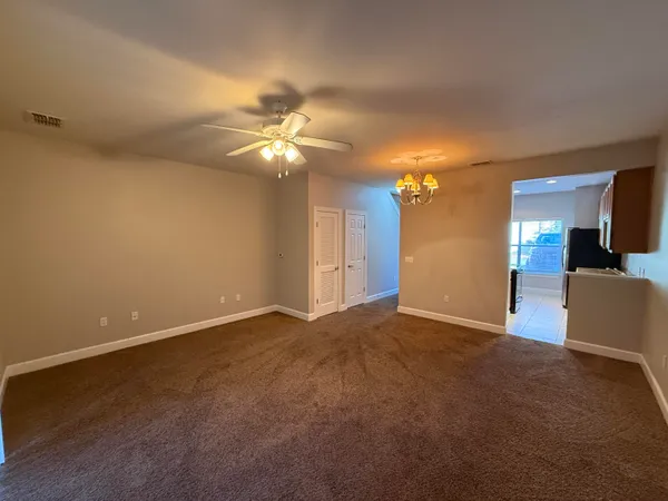 a view of an empty room with a chandelier fan
