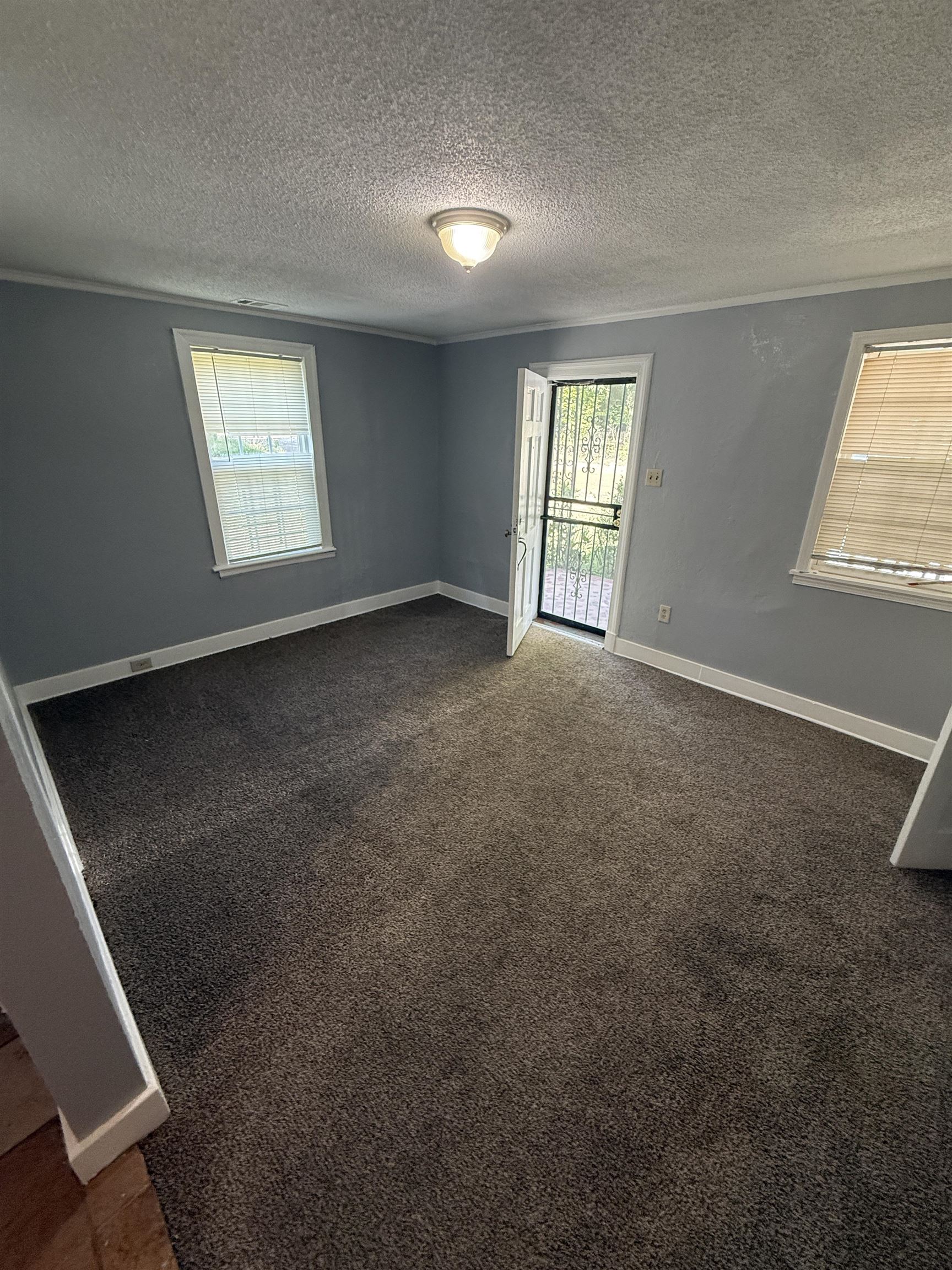 635 South Prescott Street Memphis, TN 38111 - Photo 2 of 5 Unfurnished room featuring a textured ceiling, dark colored carpet, and crown molding