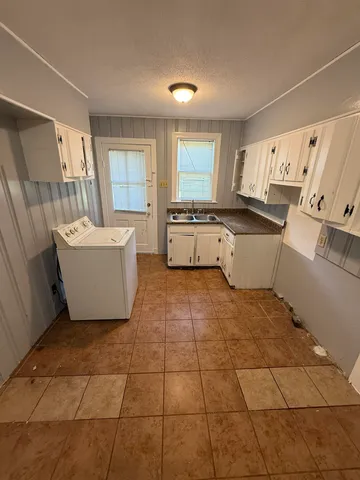 a large white kitchen with a sink a refrigerator and window