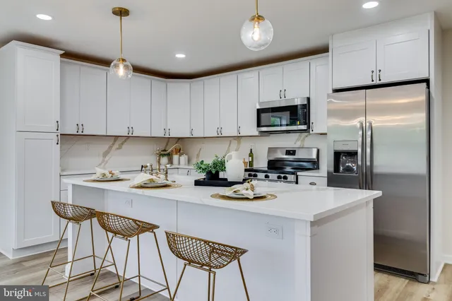 a kitchen with a refrigerator a stove a sink and white cabinets