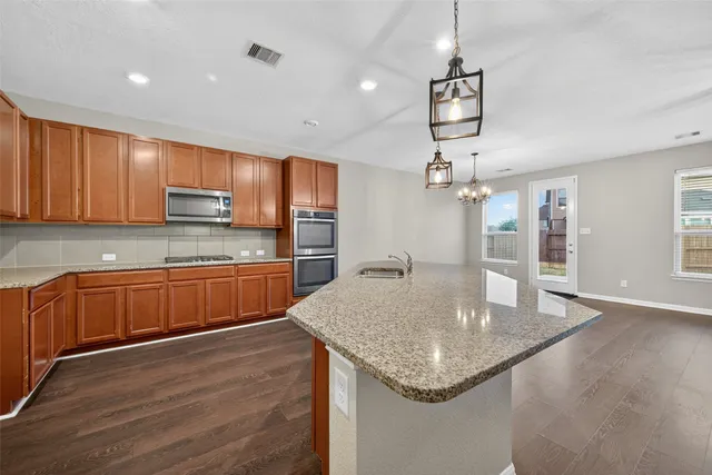 a kitchen with stainless steel appliances granite countertop a sink dishwasher and microwave with wooden floor
