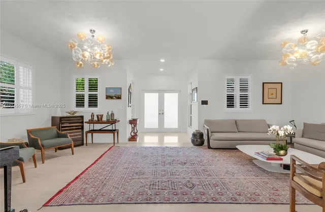 a living room with patio furniture and floor to ceiling windows
