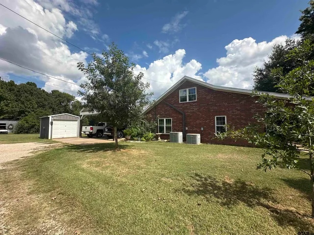 a view of a house with a big yard and large trees