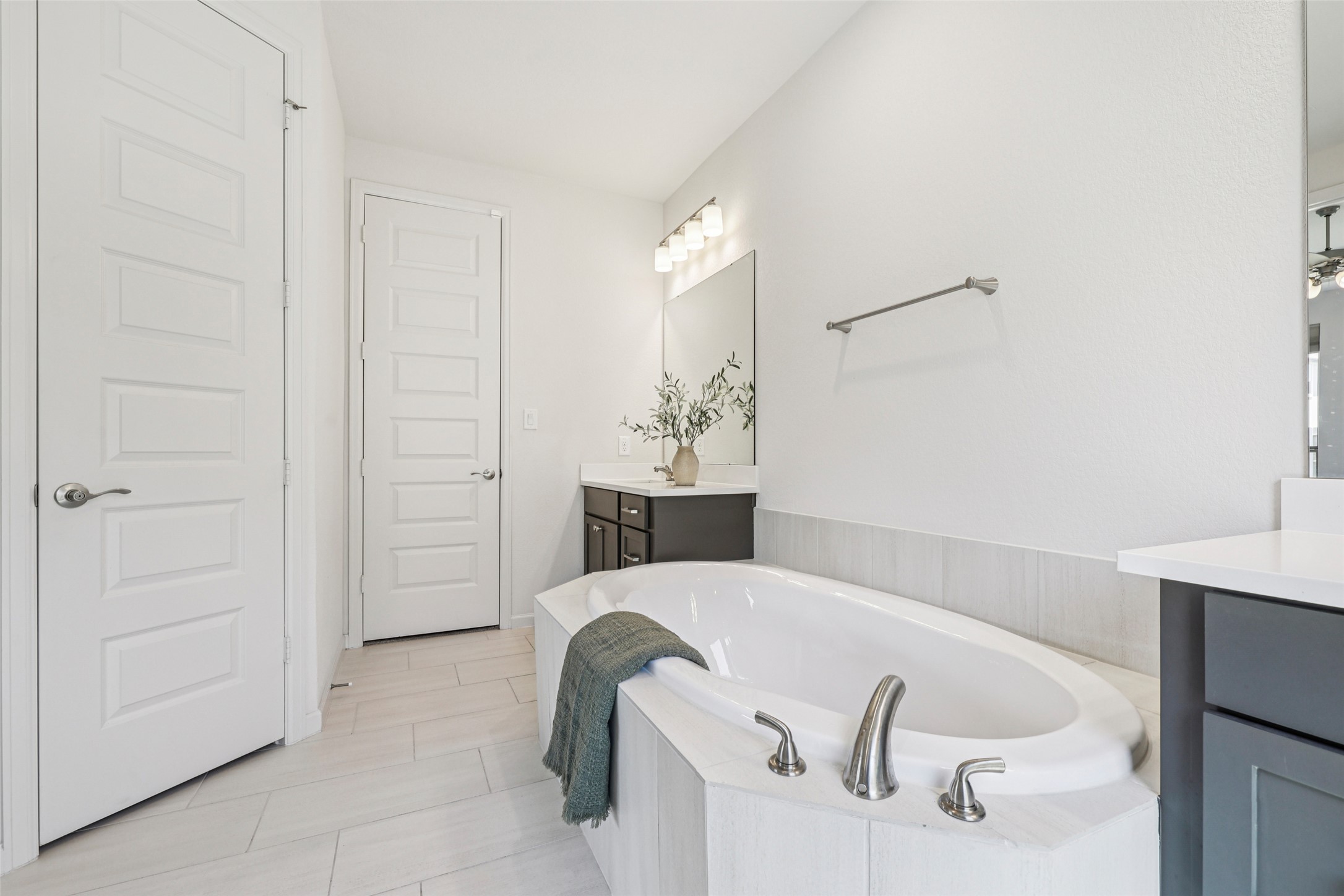 1140 Bryson Rdg Trail Leander, TX 78641 - Photo 18 of 39 Bathroom featuring a spacious built-in soaking tub, a double vanity with dark cabinetry and light countertops, and light-colored tile flooring