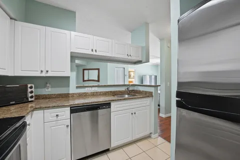 a kitchen with granite countertop white cabinets and white appliances