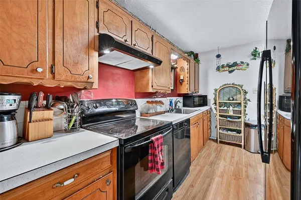 a kitchen with stainless steel appliances kitchen island granite countertop a sink dishwasher and cabinets with wooden floor