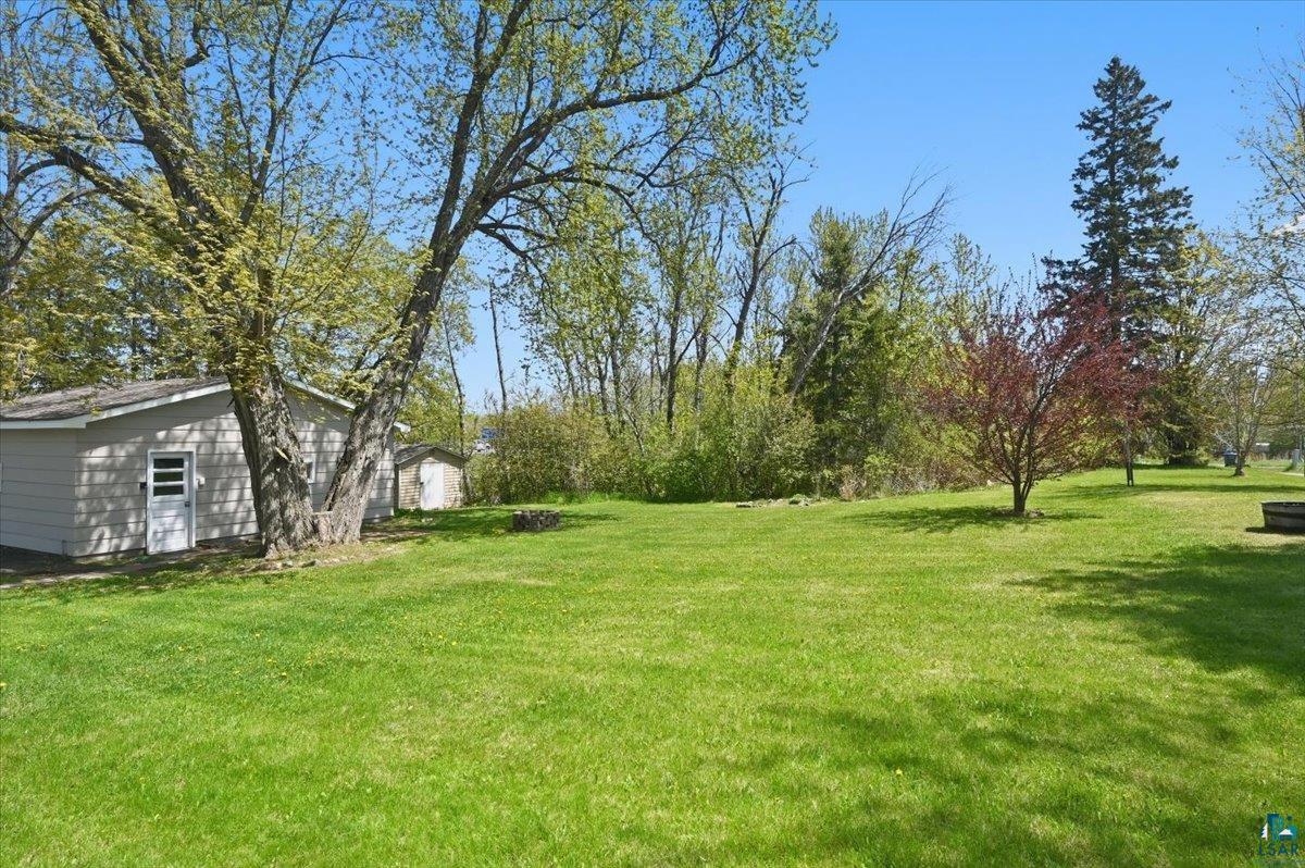 5319 East 3rd Street Superior, WI 54880 - Photo 7 of 33 Expansive green lawn with mature trees and a detached outbuilding featuring a side entry door