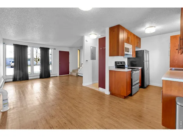 a view of a kitchen with refrigerator and wooden floor