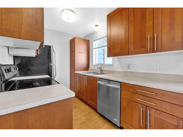 a kitchen with stainless steel appliances a sink dishwasher stove refrigerator and cabinets