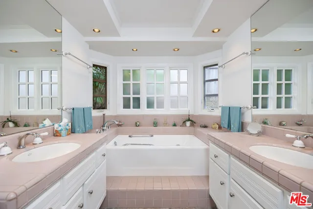 a bathroom with double vanity sinks a large mirror and a bathtub