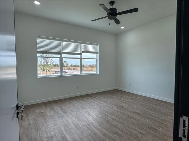 a view of an empty room with a window and wooden floor