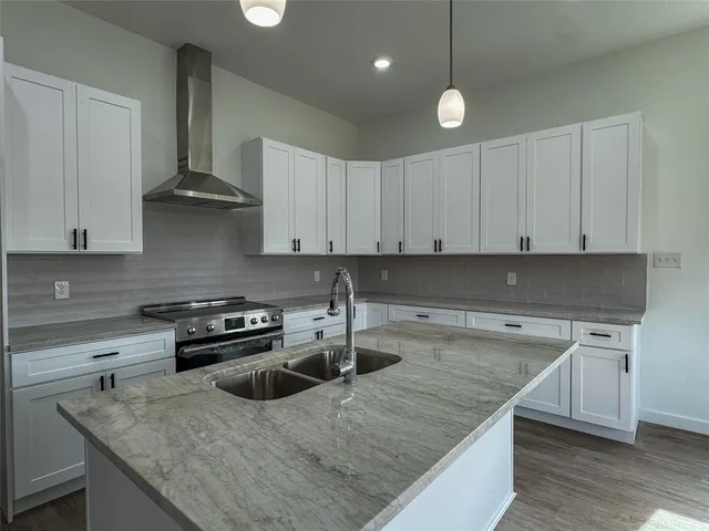 a kitchen with granite countertop a sink a stove and a wooden cabinets