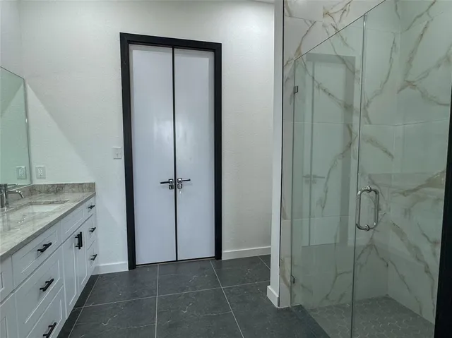 a bathroom with a granite countertop sink a mirror and a shower